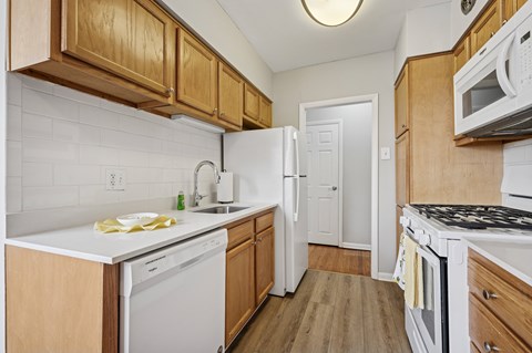 A kitchen with white appliances and wooden cabinets.