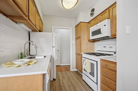 A kitchen with white appliances and wooden cabinets.