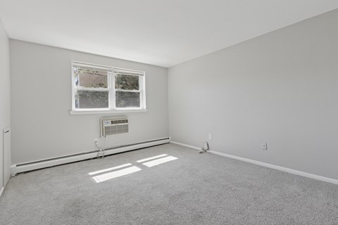 A room with a window and a carpeted floor.