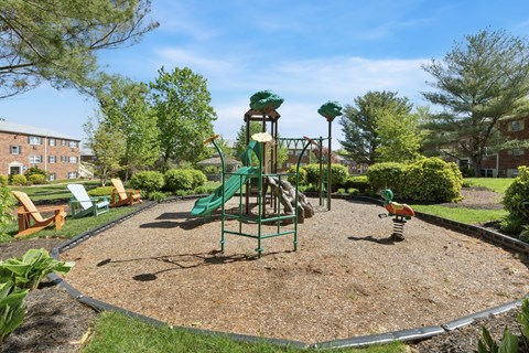 A playground with a green slide and a red and yellow swing set.