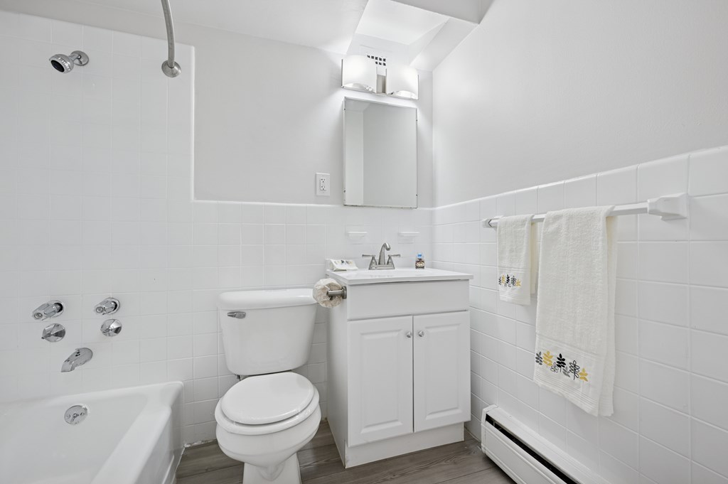 A white bathroom with a toilet, sink, and shower.