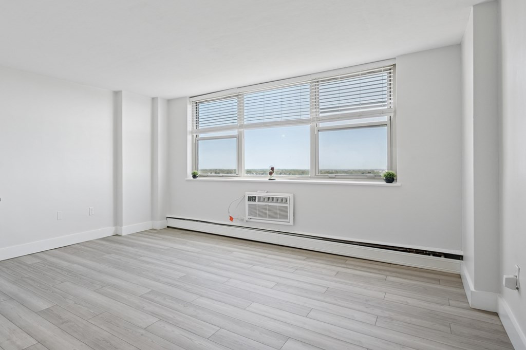 A room with a window and a wall-mounted air conditioner.