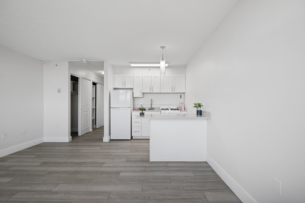 A kitchen with white cabinets and a white refrigerator.