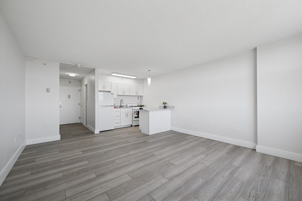 A kitchen with white cabinets and a wooden floor.