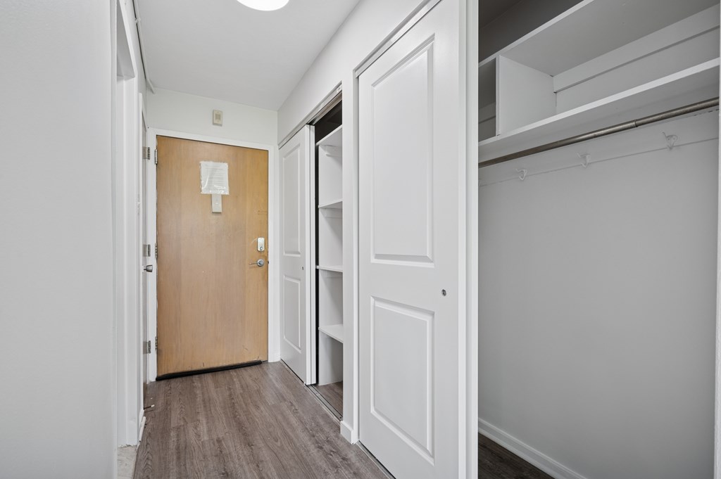 A hallway with a brown door and white walls.