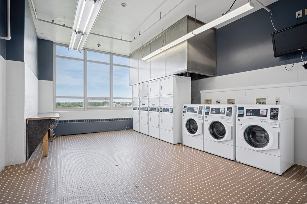 A laundry room with a row of washers and dryers.