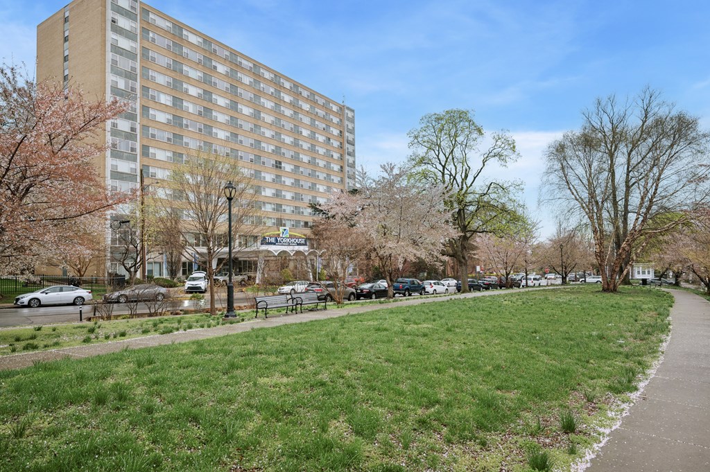 A grassy area in front of a tall building with a street sign.