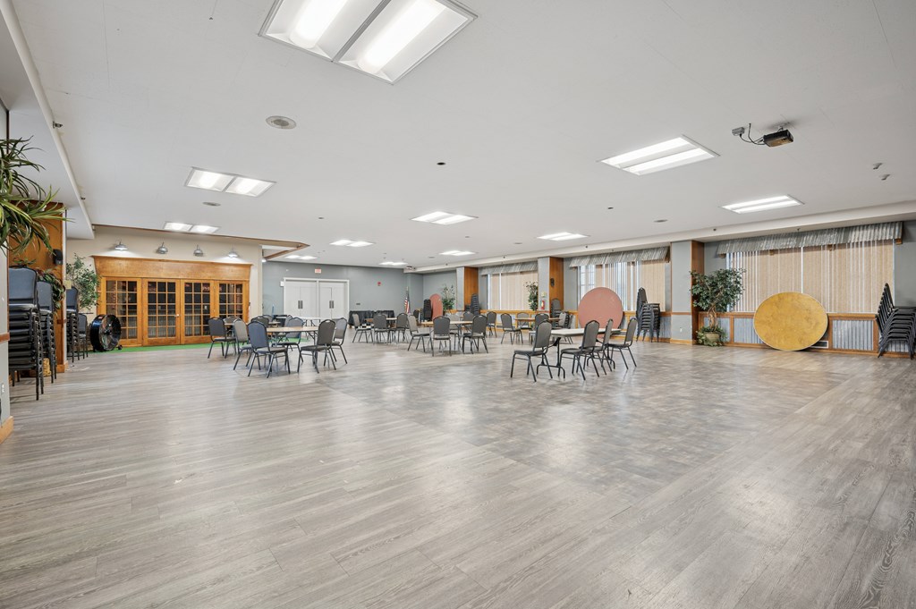 A spacious room with wooden floors and tables set up for an event.