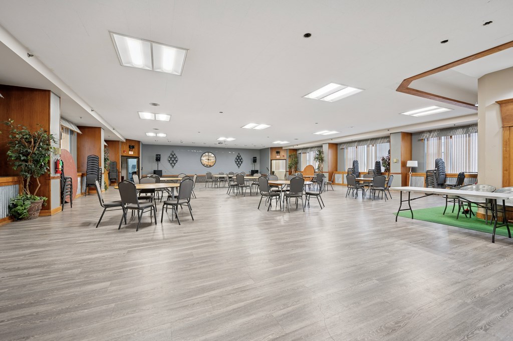 A spacious room with tables and chairs is well lit with natural light.