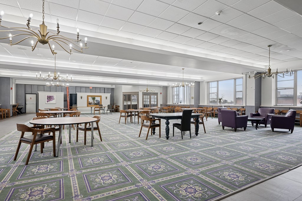 A large room with tables and chairs and a chandelier.