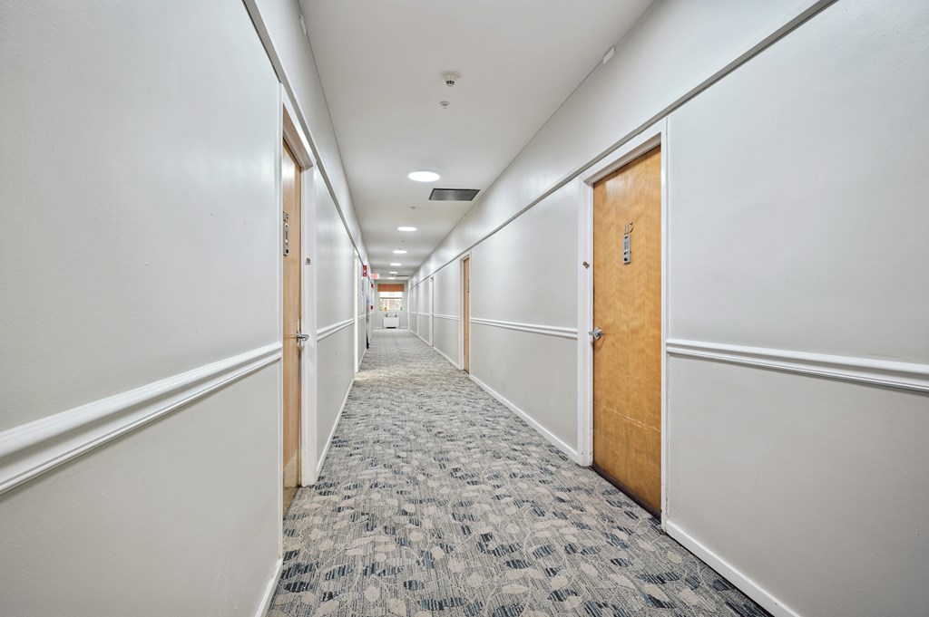 A long hallway with carpeted floors and white walls.