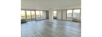 an empty living room with plank floors and windows