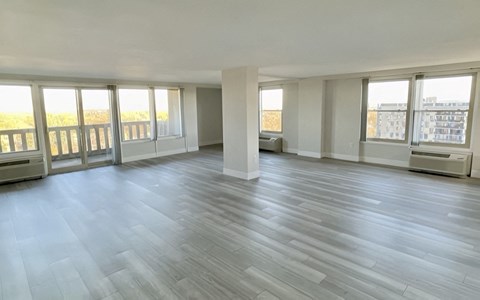 an empty living room with plank floors and windows
