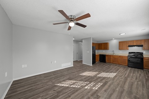 A spacious room with a ceiling fan and wooden flooring.