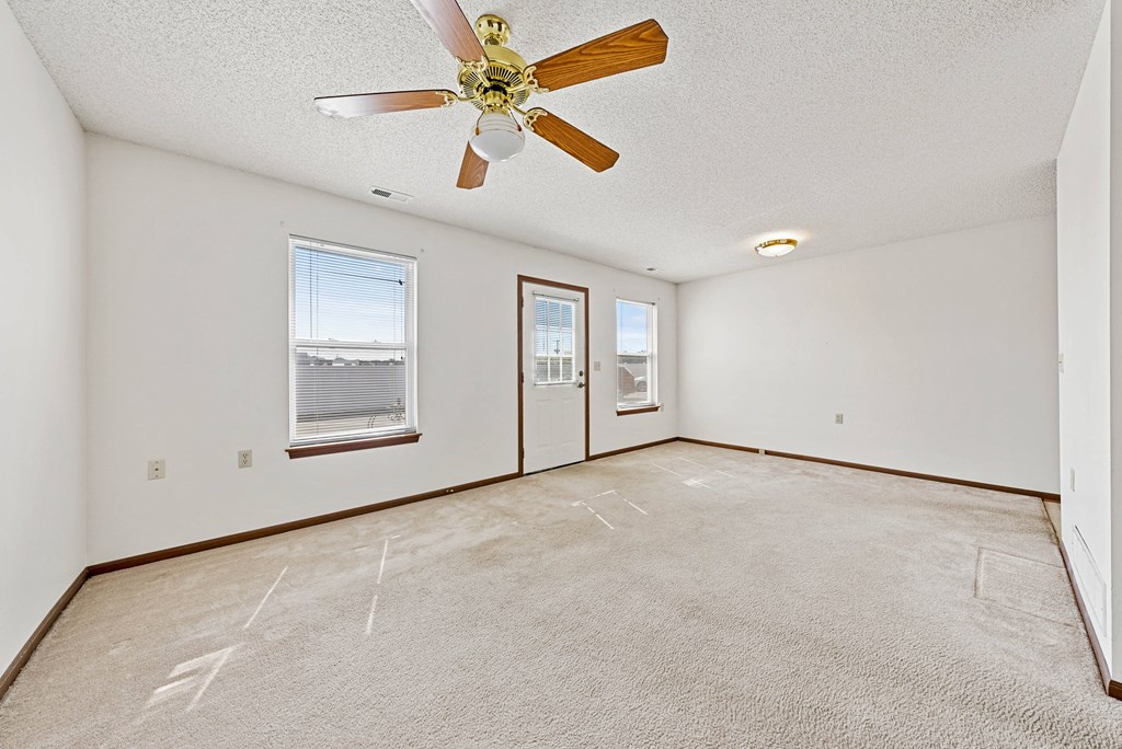 A room with a ceiling fan and carpeted floor.