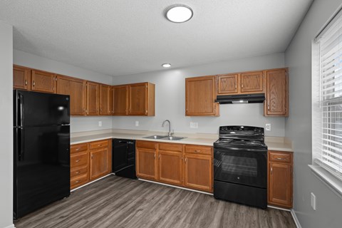 A kitchen with black appliances and wooden cabinets.