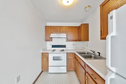 A kitchen with white appliances and wooden cabinets.