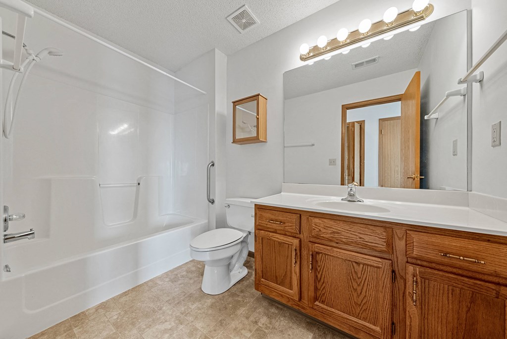 A bathroom with a white tub, toilet, and sink.