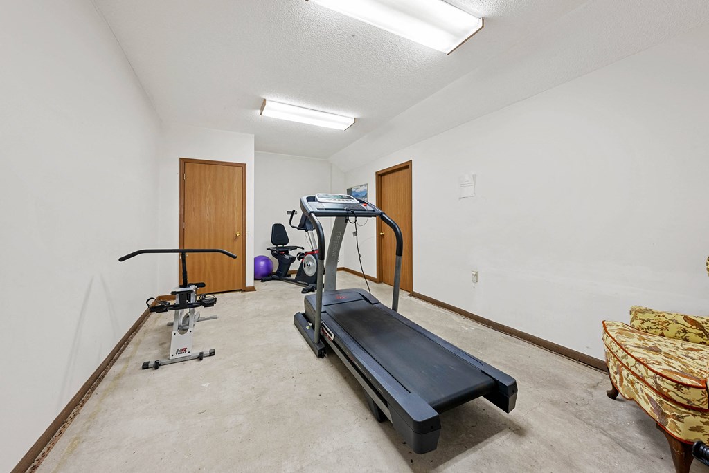 A treadmill and exercise bike are in a room with a bed.
