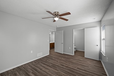 A room with a ceiling fan and wood flooring.