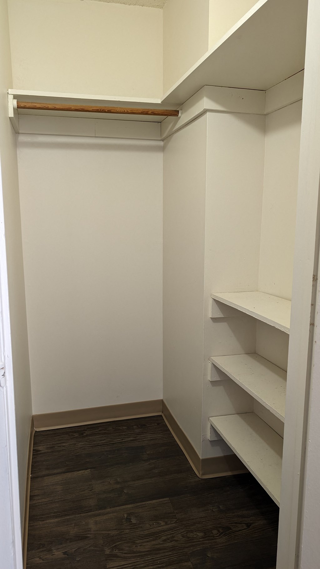 a walk in closet with shelves and a wood floor