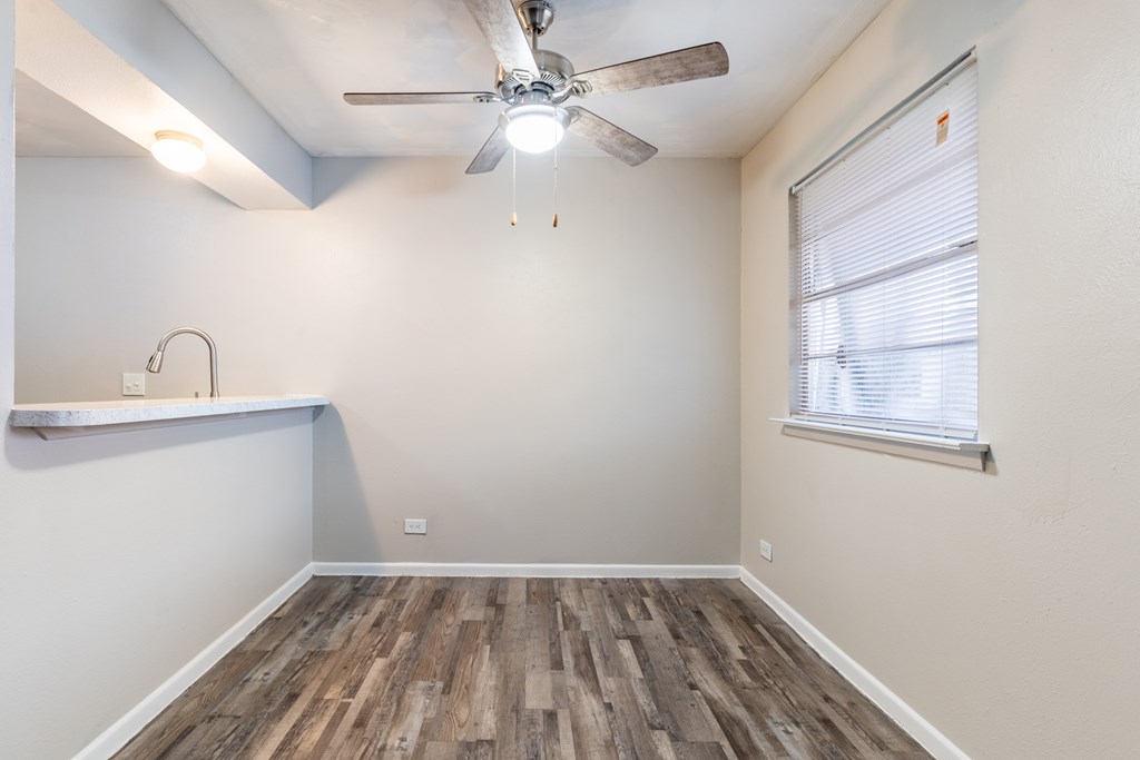 A room with a ceiling fan and wooden flooring.