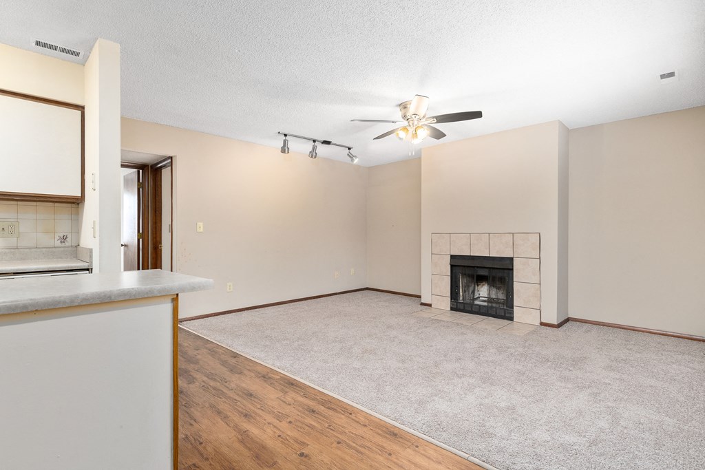 an empty living room with a fireplace and a ceiling fan