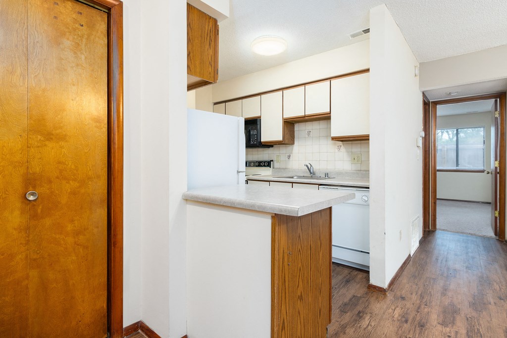a kitchen with white cabinets and a white counter top    and a door