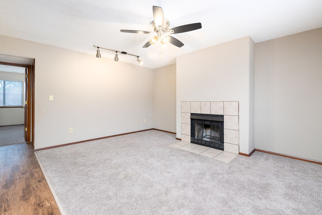 an empty living room with a fireplace and a ceiling fan