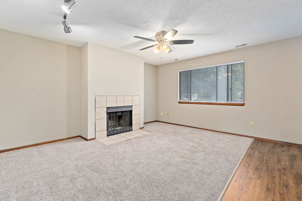 an empty living room with a fireplace and a ceiling fan