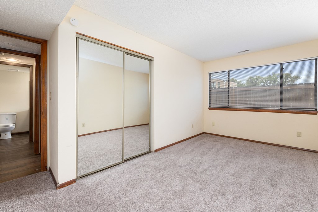 a bedroom with a large window and a door to a bathroom