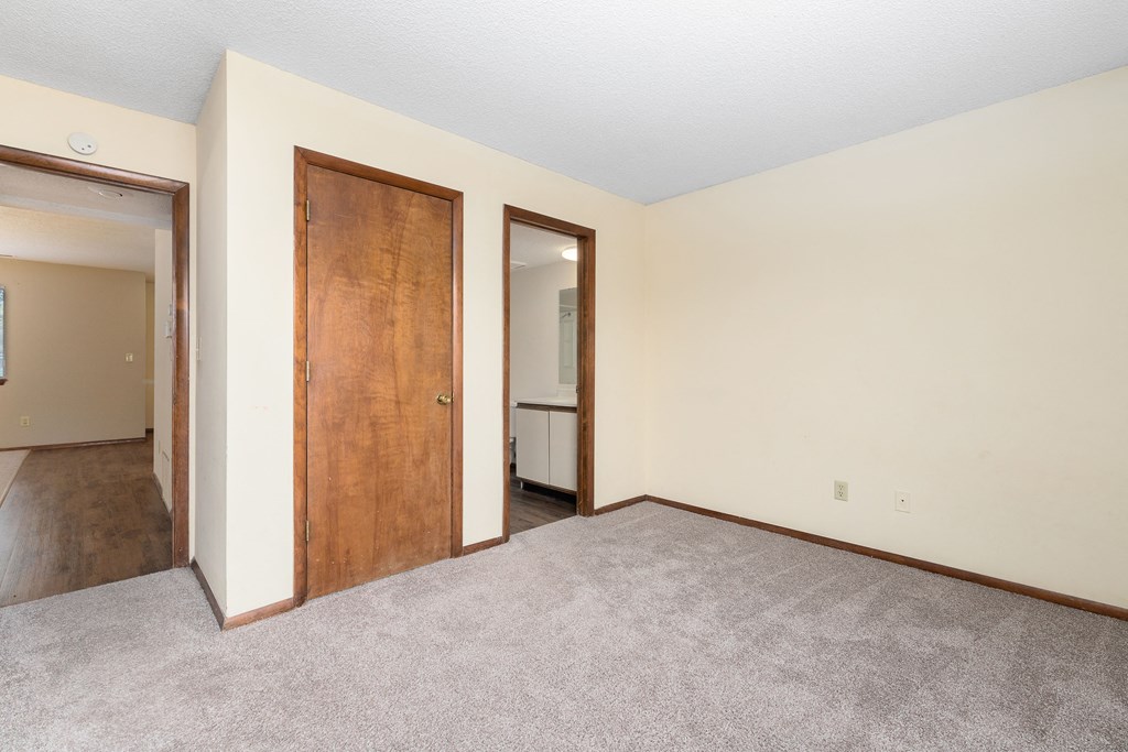 an empty living room with a door to a hallway and a closet