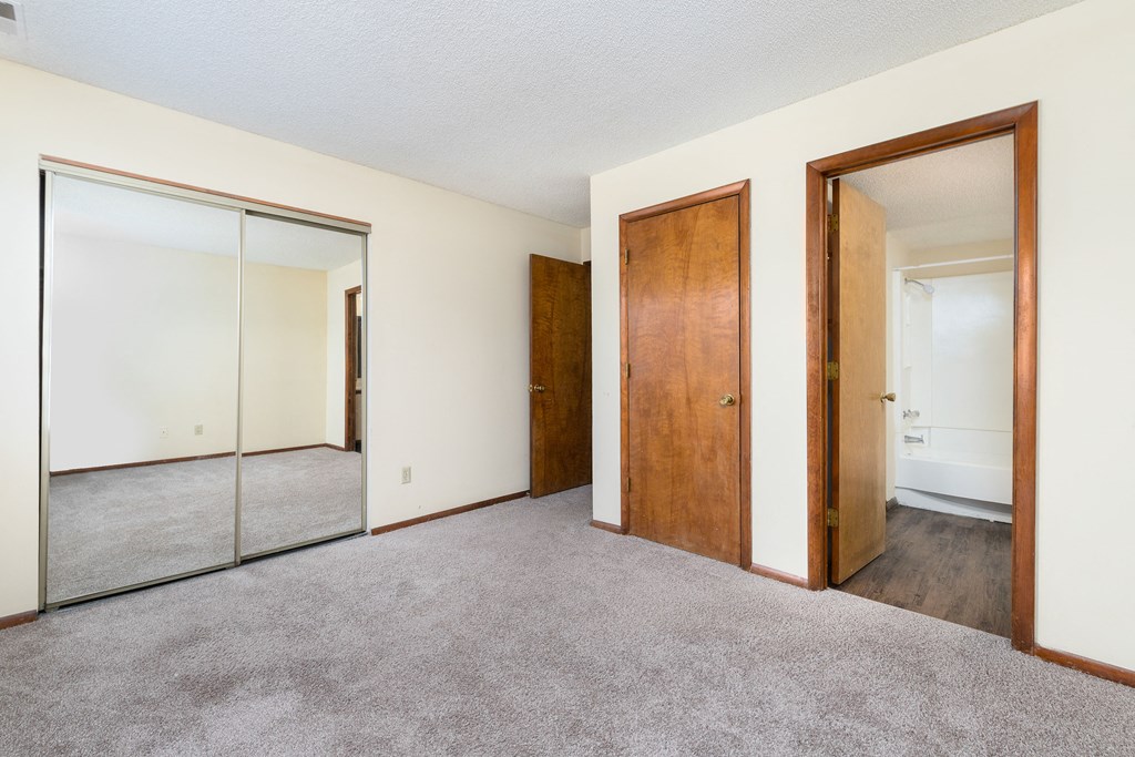 a bedroom with carpet and mirrors on the wall