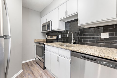 a kitchen with white cabinets and granite counter tops and black and white appliances