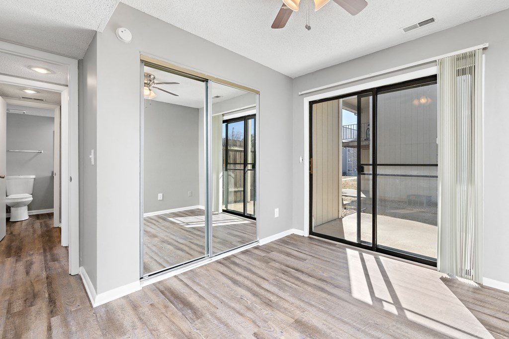 Living room with large patio door and closet with mirror doors at Eddingham in Lawrence, KS