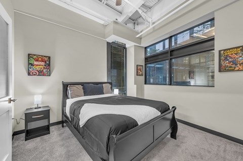 A bedroom with a large bed and two Marvel posters on the wall.