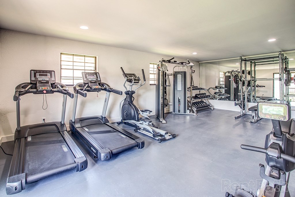 a gym with cardio equipment and weights on the floor