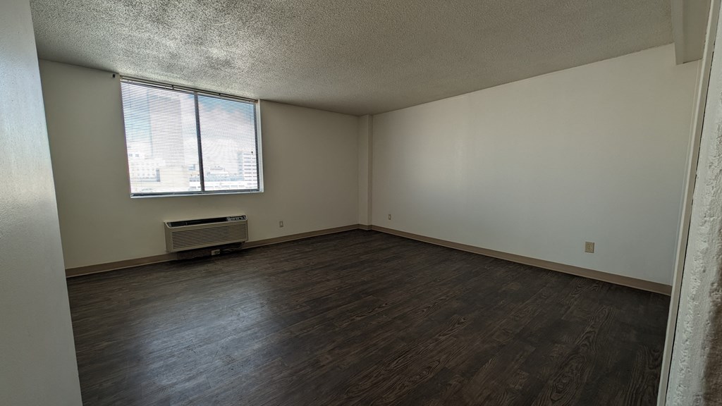 an empty living room with wood floors and a window