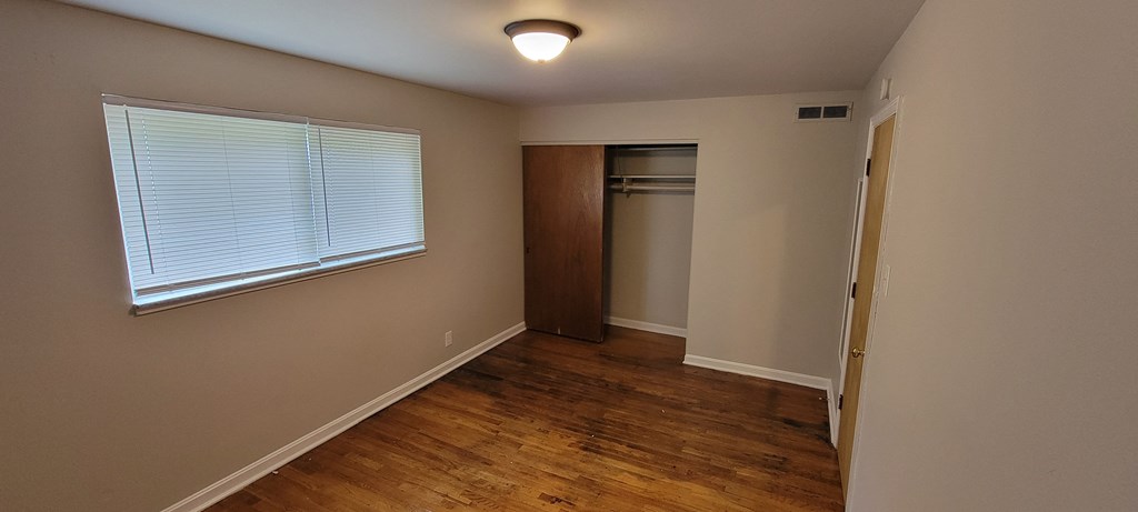 an empty room with hardwood floors and a large window