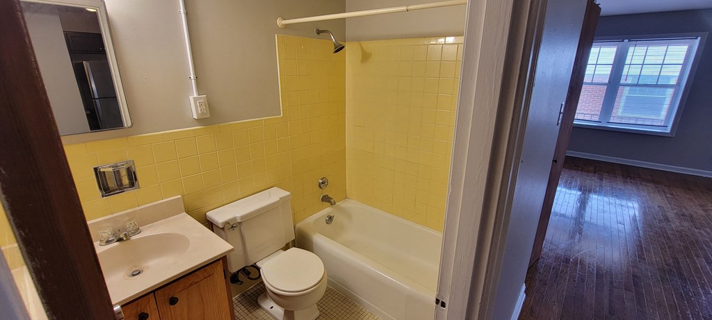 a bathroom with yellow tiles and a white bathtub