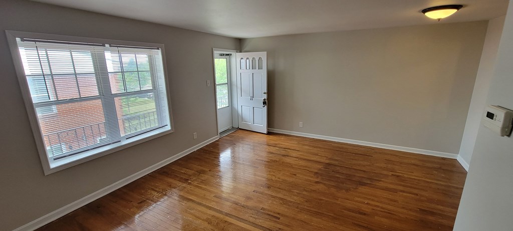 a bedroom with hardwood floors and a large window