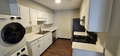 A small kitchen with white cabinets and a black stove top.