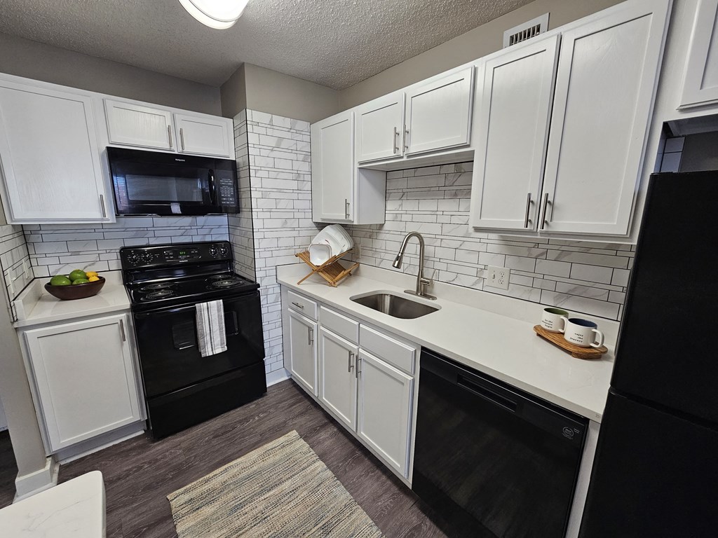an empty kitchen with white cabinets and black appliances