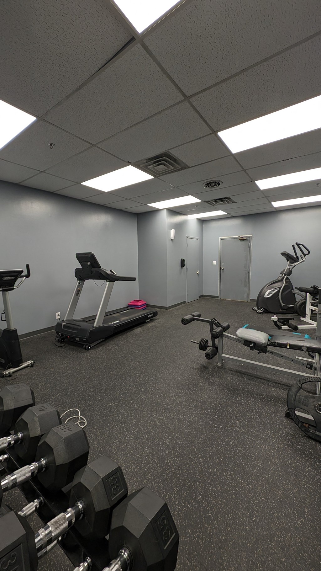 a gym with exercise equipment on the floor and a door