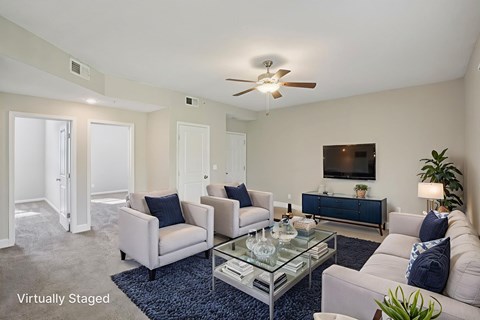 A living room with a glass coffee table and a blue rug.