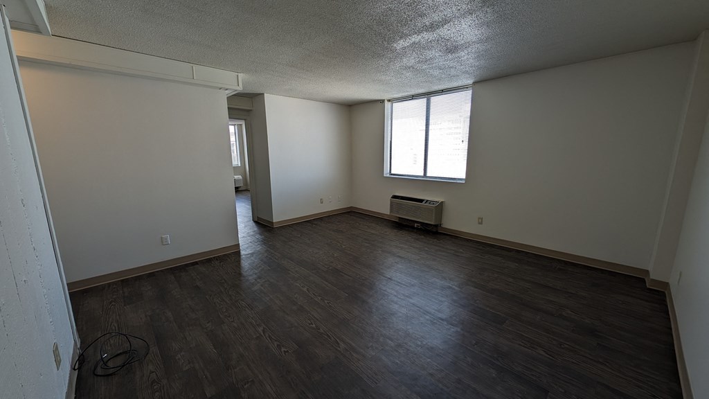 an empty living room with wooden floors and a window
