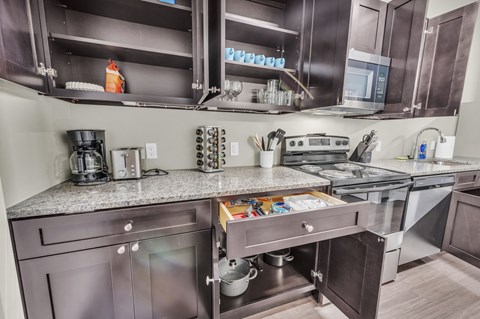 A modern kitchen with dark brown cabinets and stainless steel appliances.