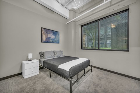 A bedroom with a bed, nightstand, and a painting on the wall.