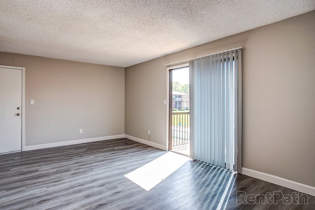 an empty living room with a sliding glass door to a balcony