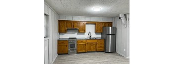 view of a kitchen with a sink stove and fridge with wood cabinentry